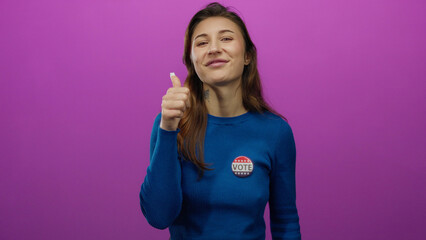 Woman smiling with thumbs up and a vote badge on a pink background, expressing support and civic...