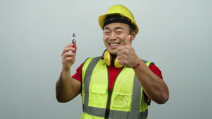 Young man wearing construction gear and a hard hat on white background displays a vape device with...