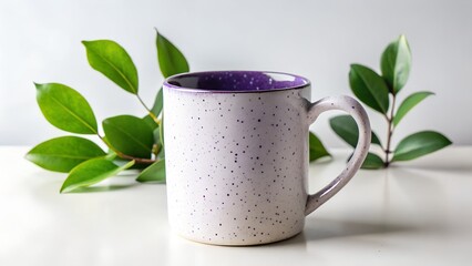 A speckled purple and white ceramic mug sits on a white table, flanked by vibrant green leaves