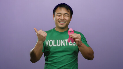 Asian man volunteer holding pink ribbon against purple background promoting breast cancer awareness...