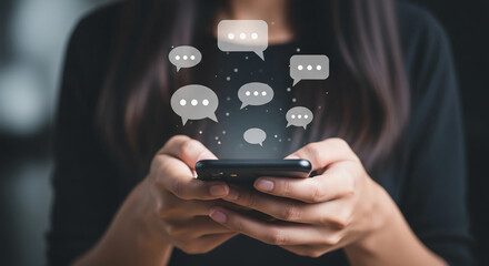 Close-up of hands holding smartphone, with speech bubbles floating above, symbolizing communication, social media, or online messaging