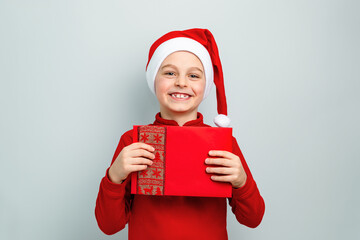 Cheerful boy in Santa hat holding an envelope, postcard, greeting, letter to Santa Claus ,...