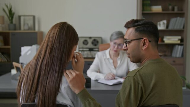 Back view of empathic Indian man consoling crying wife during family counselling session in therapists office