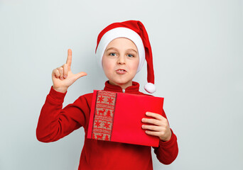 Cheerful boy in Santa hat holding an envelope, postcard, greeting, letter to Santa Claus ,...
