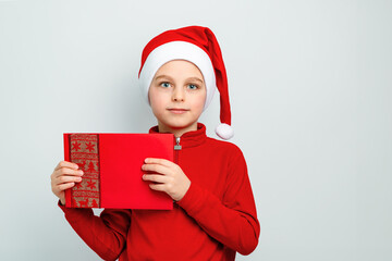 Cheerful boy in Santa hat holding an envelope, postcard, greeting, letter to Santa Claus ,...