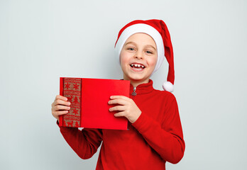 Cheerful boy in Santa hat holding an envelope, postcard, greeting, letter to Santa Claus ,...