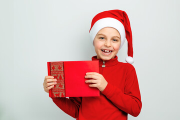 Cheerful boy in Santa hat holding an envelope, postcard, greeting, letter to Santa Claus ,...