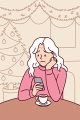 Elderly woman sits alone indoors on Christmas night holding tea and feeling sad and lonely