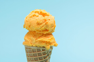 Orange ice cream cone isolated on blue background.