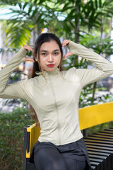 Beautiful asian woman sitting in the park to rest after exercise. Women relax and enjoy the...