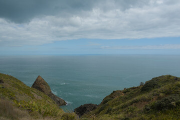 A vast coastal landscape features a long sandy beach, a turquoise ocean with distant islands, and...