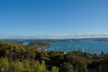 A vast coastal landscape features a long sandy beach, a turquoise ocean with distant islands, and...