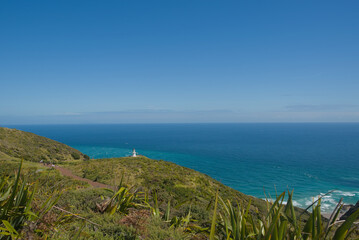 A vast coastal landscape features a long sandy beach, a turquoise ocean with distant islands, and...
