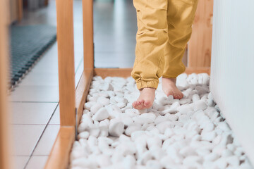 The child walks on the stones with his bare feet. Treatment of valgus foot in children or todlers....