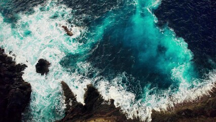 The sea is beating against the rocks on the shore. Bird's-eye view. Frothy waves from a drone