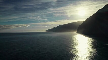 The sun rises over the mountains on the seashore. View from the drone from the sea
