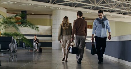 People with bags in their hands are walking in the waiting room of a train station or airport