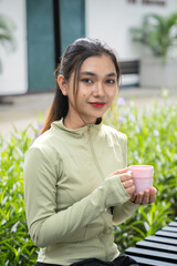 Asian woman drinking mineral water after exercising in the park. Beautiful fitness athlete woman...