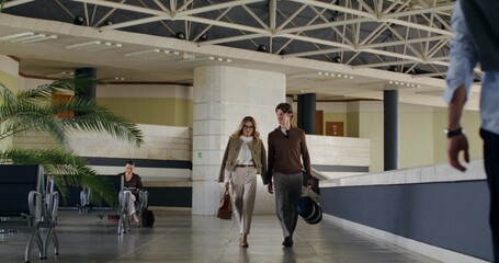 A man and a woman talk as they walk through the waiting room at a train station or airport