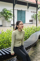 Beautiful asian woman sitting in the park to rest after exercise. Women relax and enjoy the...
