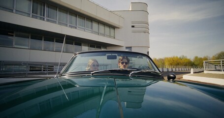 Happy young people driving a convertible on a sunny day. Wide-angle shooting, front view