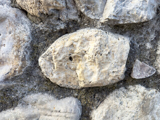 Close-up of natural stone wall texture with rough gray and beige rocks