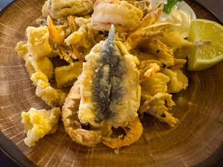 Assorted seafood tempura with lemon and dipping sauce on wooden plate