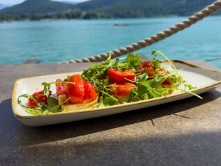 Fresh bruschetta appetizer with arugula and cherry tomatoes by scenic lake view