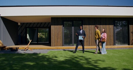 The realtor shows the house to the buyers. They walk around the backyard and talk.