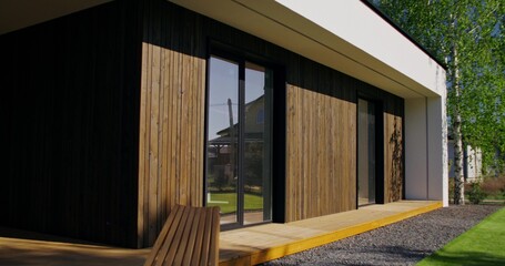 The facade of the house with panoramic windows, close-up. A sunny summer day, no people