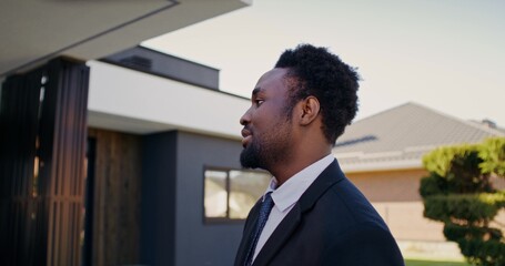 The realtor talks to the buyers standing near the house. Close-up of his smiling face