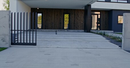 The facade of a stylish minimalist modern cottage with a well-kept house territory on a summer day....
