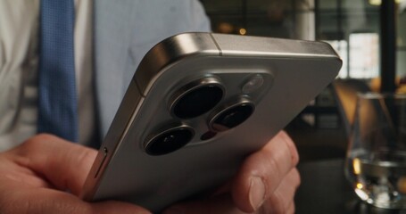 A man uses mobile phone and laptop while sitting at a desk in the office. Close-up of his hands,...