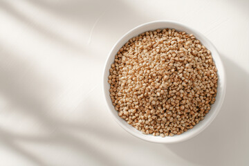 Raw buckwheat groats served in a ceramic bowl on clean white background