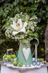 Blumenstrauß mit weißer Lilie, einjährigem Berufkraut (Erigeron annuus) und Wiesenkerbel (Anthriscus sylvestris) im vintage Krug
