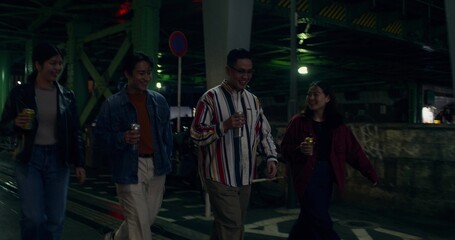 Fototapeta premium A walk through the city at night. A group of young people spend time together. They drink from tin cans.