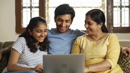 Family looking at a laptop together, indoors on the couch - Powered by Adobe