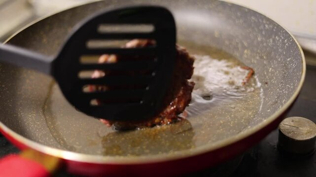 Horizontal 4K video close up. 60 fps. Chef flips round burger patty. Cook turns cutlet on frying pan with spatula. Meat, ground beef, pork, lamb is fried in oil. Concept of healthy food, no vegan cafe