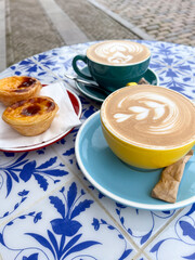 Vibrant coffee cups with latte art and delicious pastries on a beautifully patterned table, creating a delightful atmosphere for a relaxing summer vacation experience