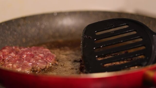 Horizontal video close up. 60 fps. Cook flips round burger patty. Chef turns cutlet on frying pan with spatula. Ground meat, pork, beef, lamb is fried in sunflower oil. No vegan cafe, lunch, dinner