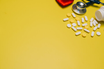 Medical flat lay concept. Medical Supplies and Yellow Pills with Stethoscope on Bright Yellow...