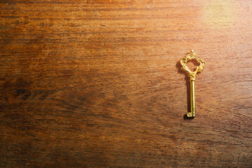 Vintage Golden Key on a Rustic Wooden Table Surrounded by Natural Light and Warm Tones