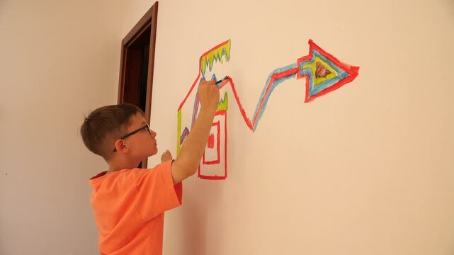 Child painting rocket ship on wall with brush and tempera colors