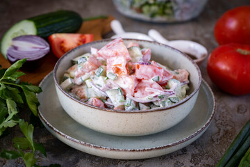Delicious fresh vegetable salad with sour cream. Salad with tomatoes, cucumbers, and onions for lunch. Close-up