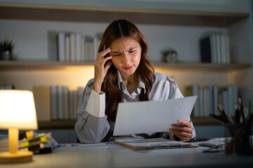 Late Night Frustration. Young woman feeling stressed while reviewing papers.