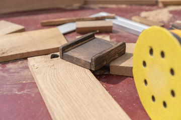 A woodworking setup with a yellow sanding disc, small wooden blocks, screws, and cut wood pieces spread across a surface