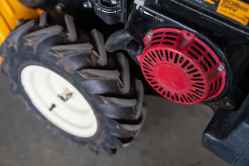 compact industrial machine engine with black rubber tire and red recoil starter housing in workshop showing rugged design mechanical components for construction and maintenance equipment