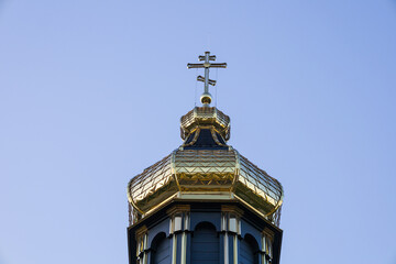 A stunning golden dome adorned with a cross rises above an old church, framed by a bright blue sky...
