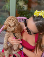 young woman in red dress sitting and holding dog on lap

