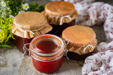 Plum jam in glass jars on a gray table. Delicious fruit jam in jars for dessert. Close-up